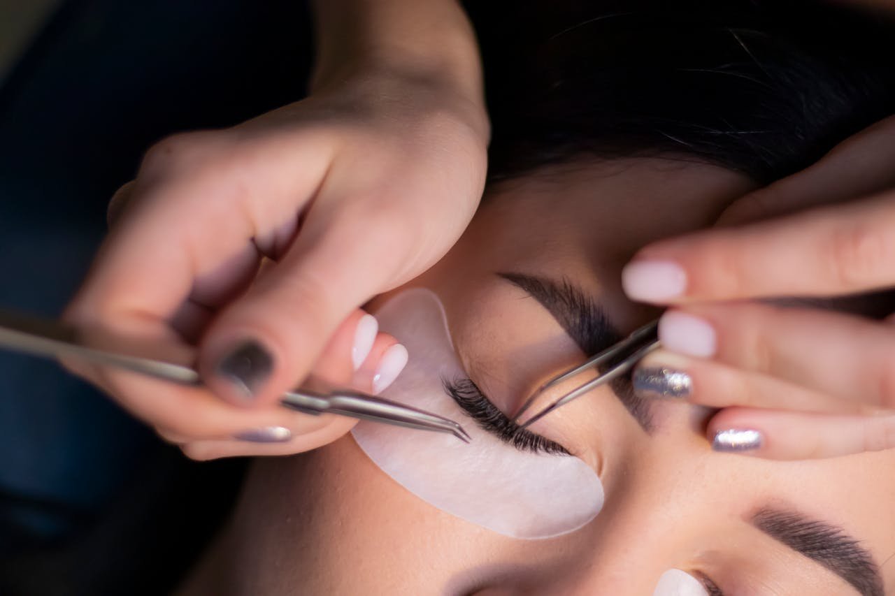 Detailed view of a beautician applying eyelash extensions to a womans eyes.