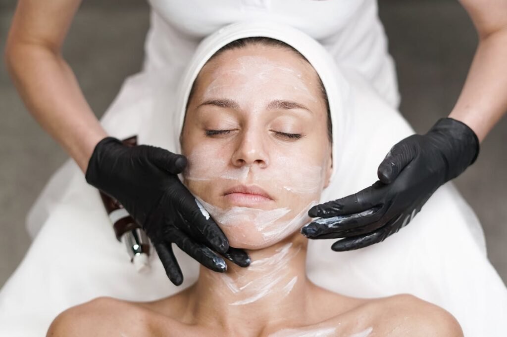 Woman receiving a facial treatment at spa, with beautician applying mask in a relaxing setting.
